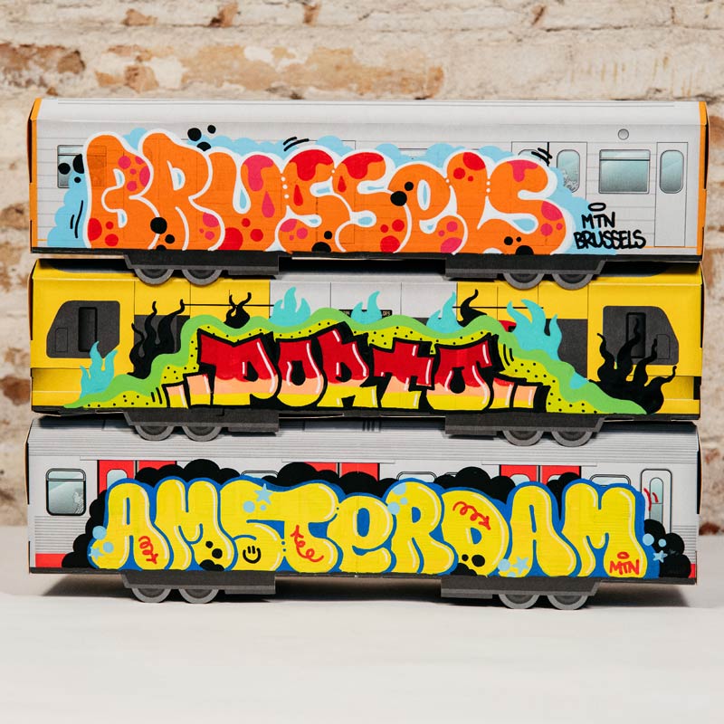 Custom painted miniature MTN Systems train car featuring vibrant graffiti tags and wildstyle lettering on a wooden table.